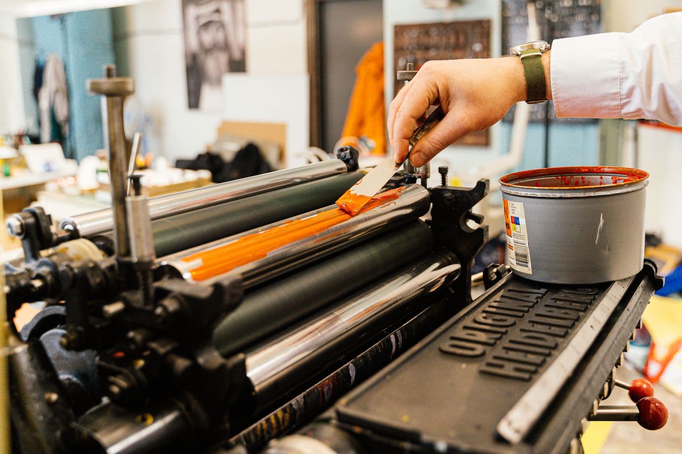 Orange ink being spread across the rollers of a printing press