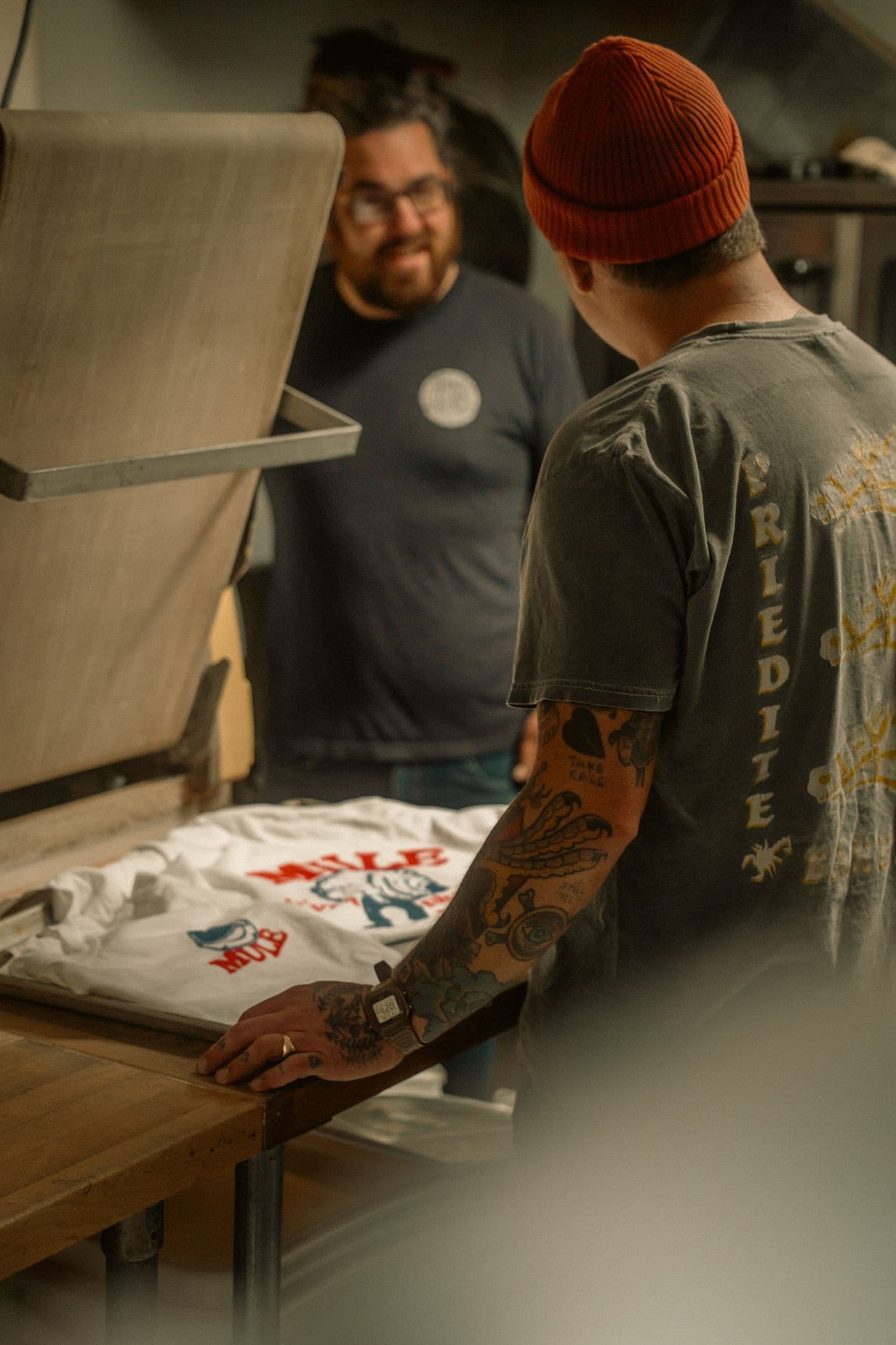 Two printers checking a freshly printed shirt in the workshop